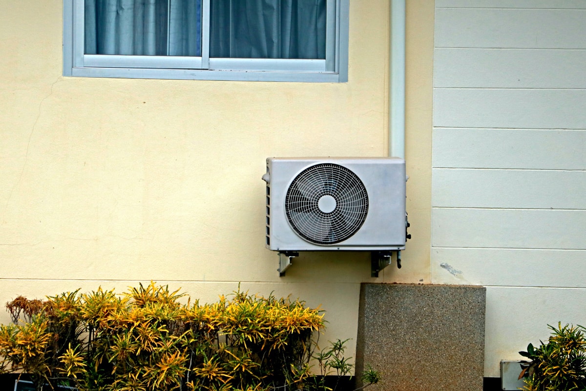 A heat pump mounted on the wall of a house.