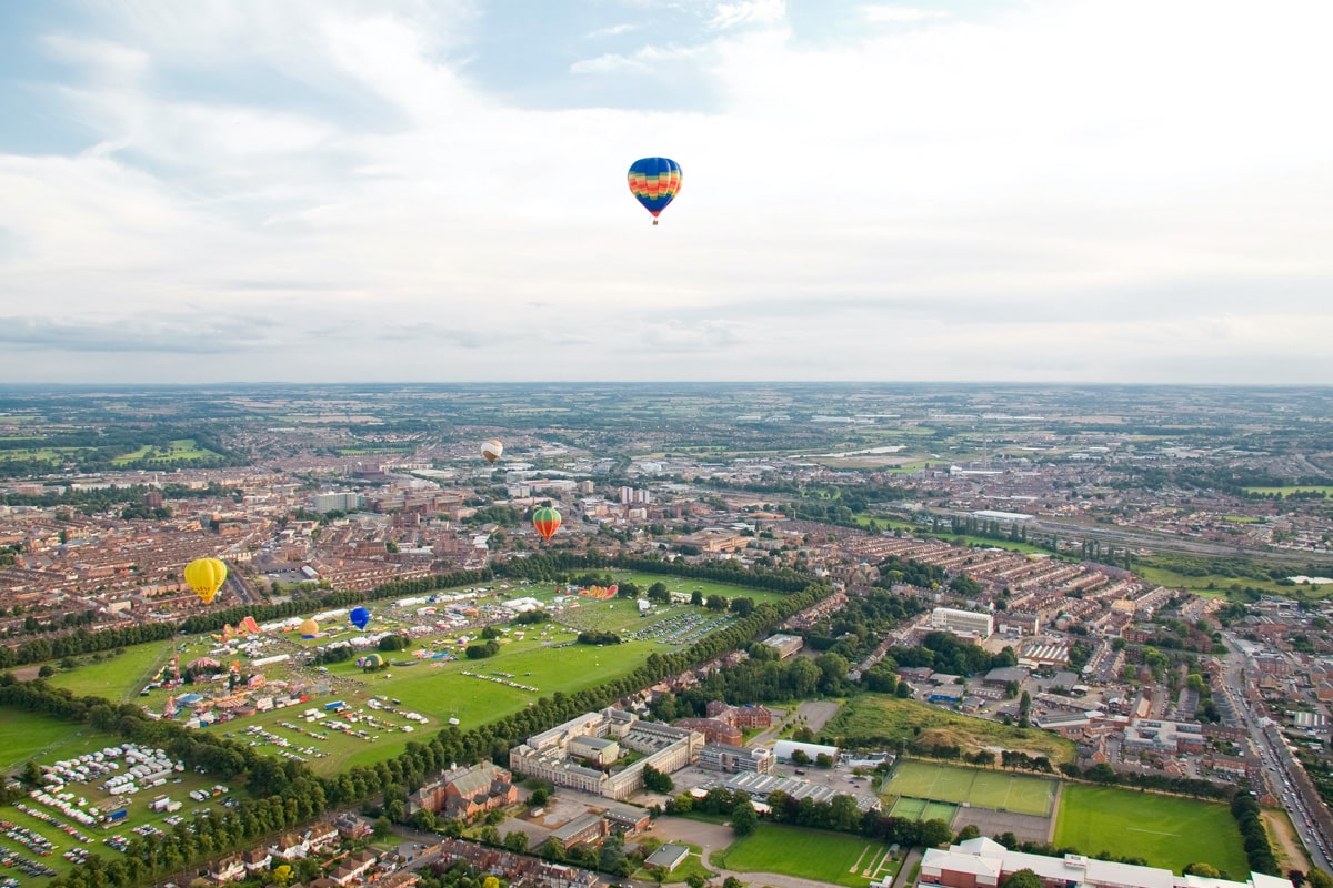 An aerial view of Northampton Racecourse with a hot air balloon flying above it.