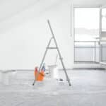 An A-frame ladder in the middle of a room that is being redecorated.