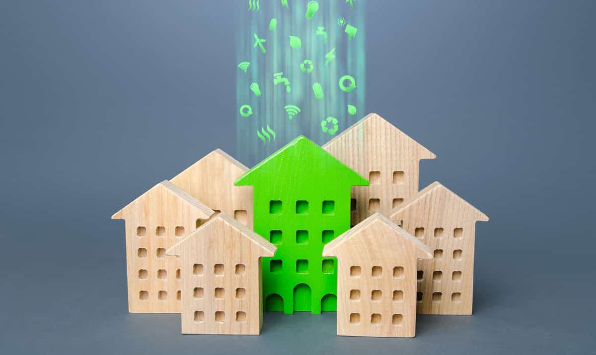 Wooden model houses. A green building stands out among other houses.