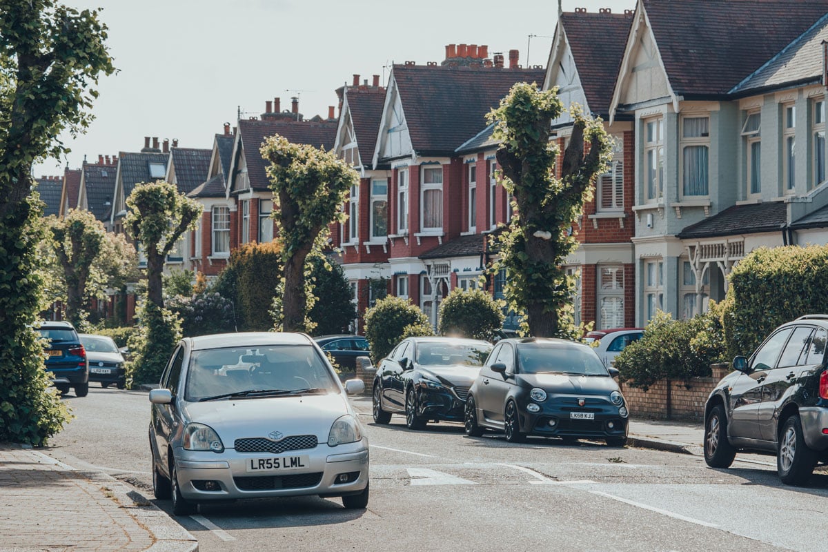 Cars parked in front of houses on both sides of a street in Palmers Green, a suburban area in the London Borough of Enfield in North London, England.