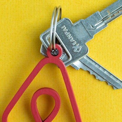 Keys on a yellow background with a keyring with the Airbnb logo on it.