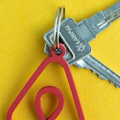Keys on a yellow background with a keyring with the Airbnb logo on it.