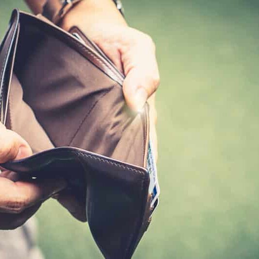 A man opens his wallet to reveal that it is empty. Represents no money