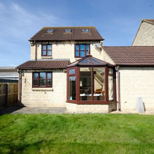 Rear garden of a four bedroom detached house with glass conservatory and link detached garage.