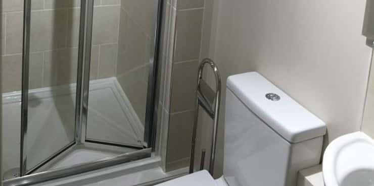 An en-suite bathroom in an HMO with a sink a toilet and a walk-in shower.