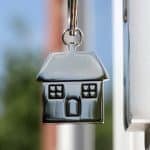 House key on a house shaped silver keyring in the lock of a door
